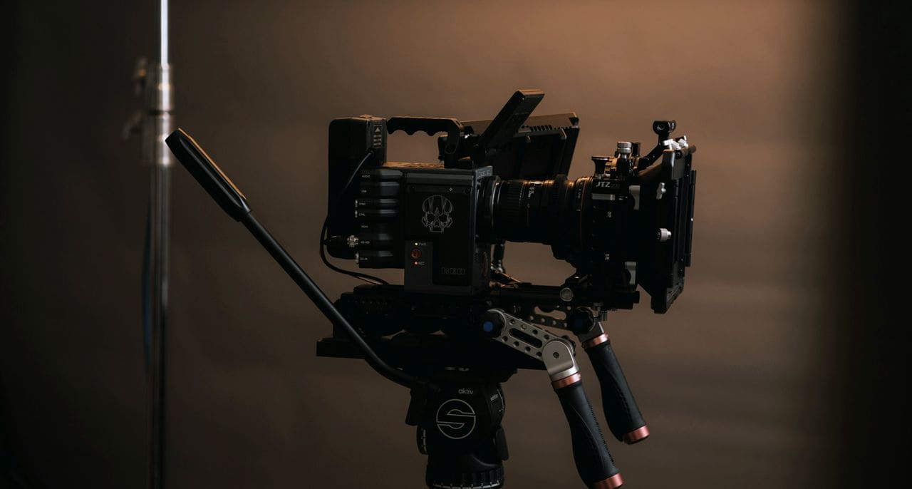 A cinema camera rigged on a tripod in a dimly lit studio