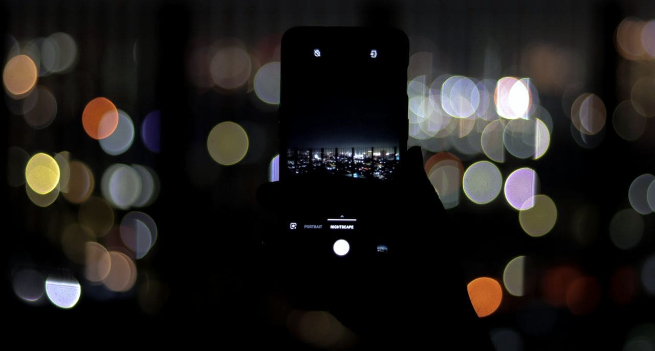 A smartphone held up at night against blurred city lights